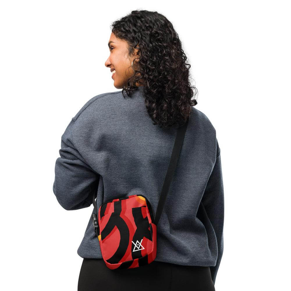 Woman wearing Hora Mágica Utility Crossbody Bag with red and black design showcasing adjustable straps and spacious pockets.